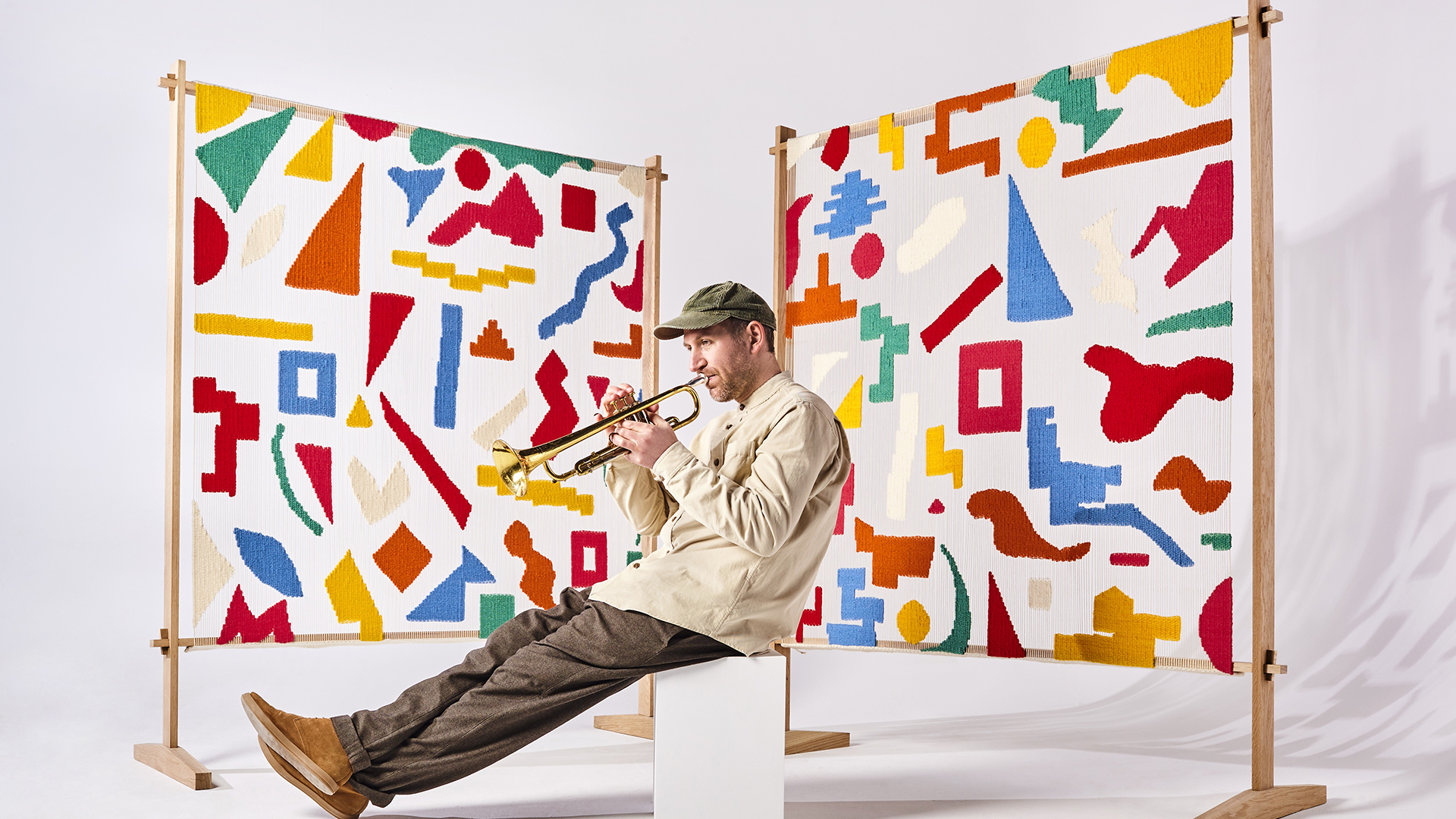 Matthew Halsall playing a trumpet in front of a coloured screen