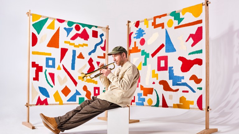 Matthew Halsall playing a trumpet in front of a coloured screen