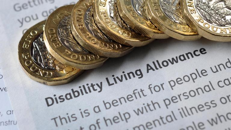 Pound coins on a piece of paper with disability living allowancve
