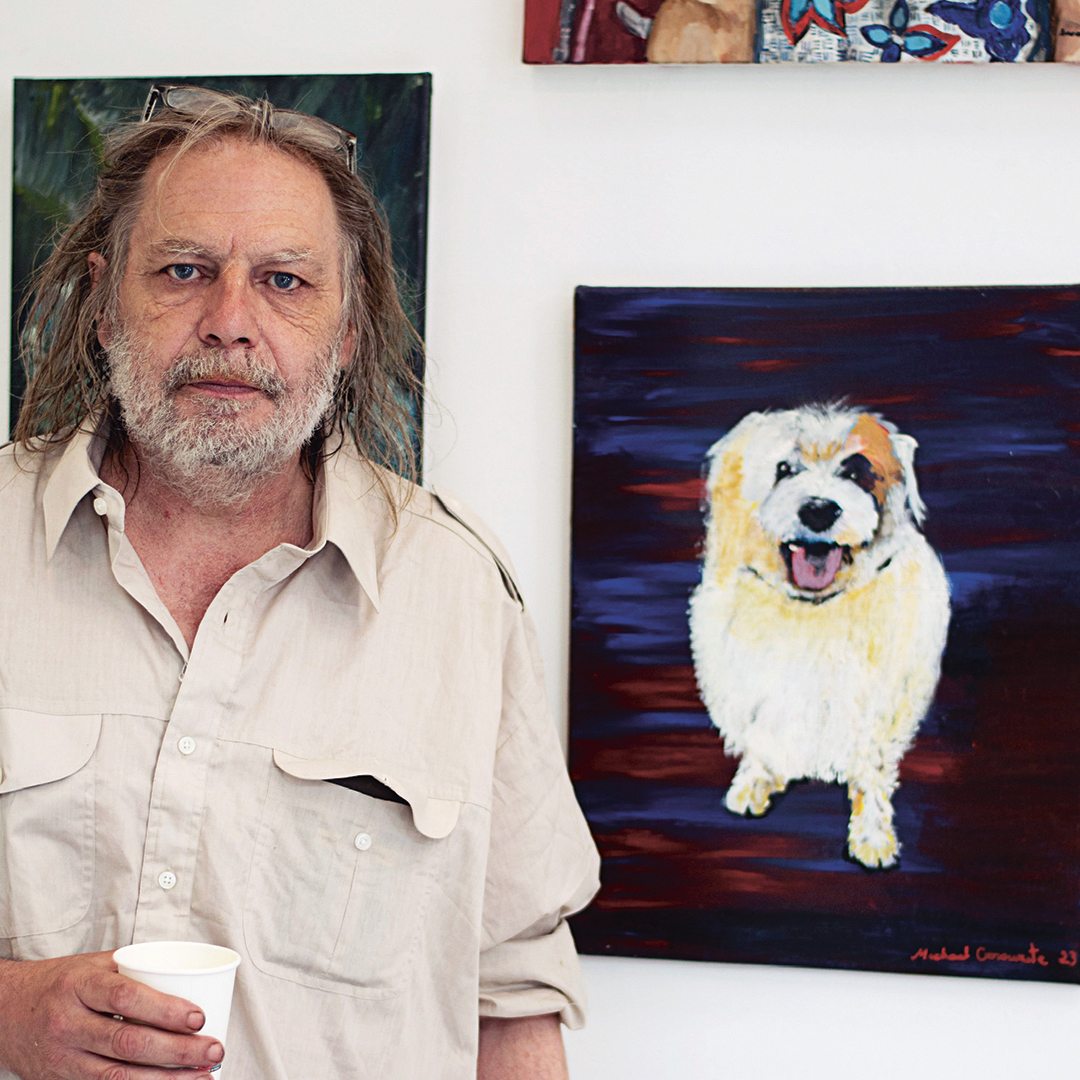 Artist beside a painting of a dog