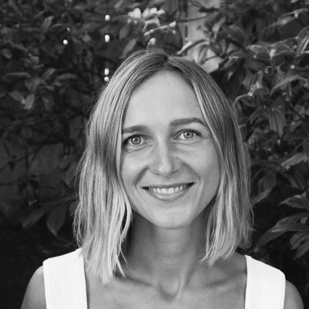 Woman smiling at the camera with blond hair and a white vest