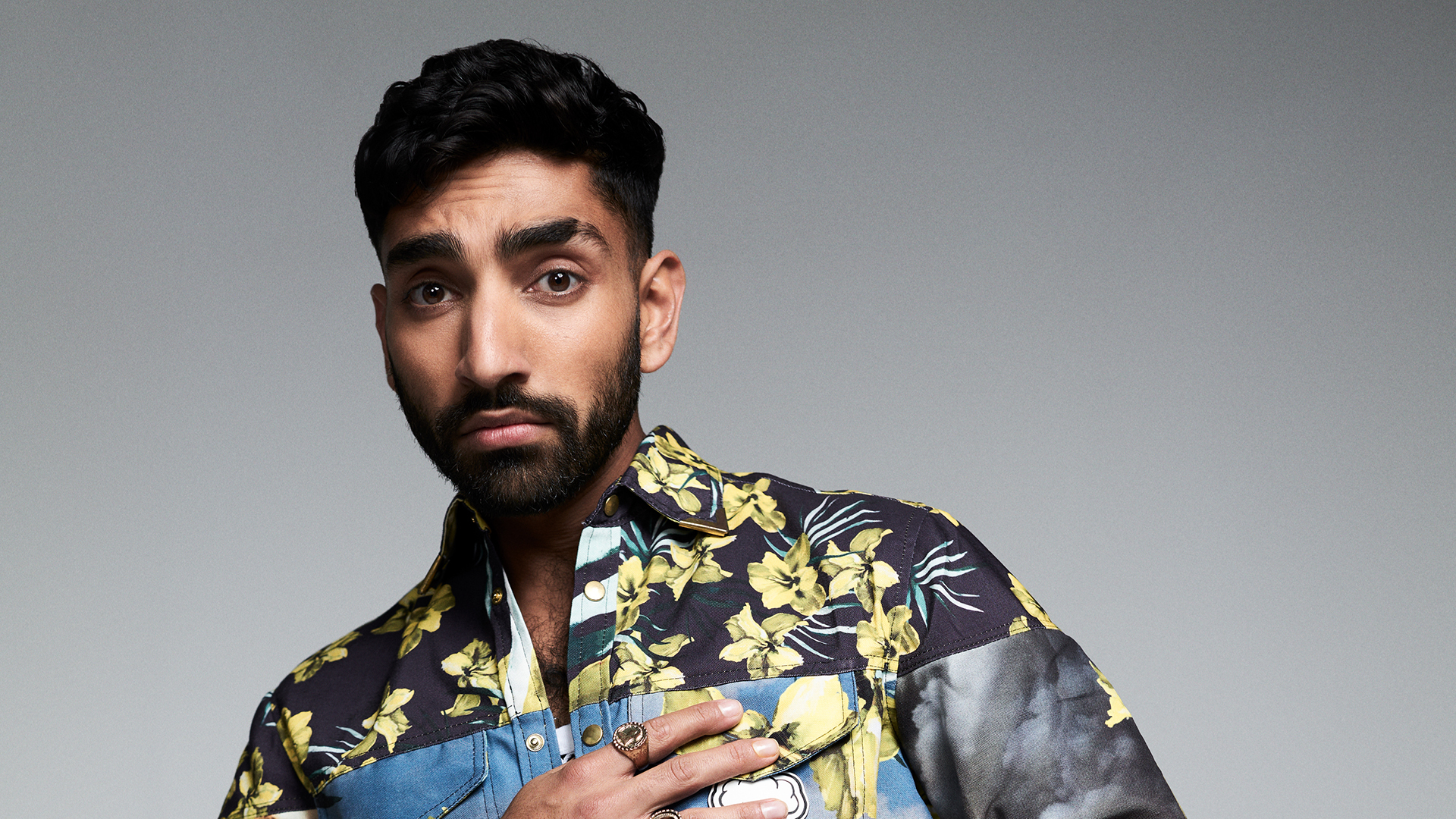 Man with black hair, a beard and colourful jacket