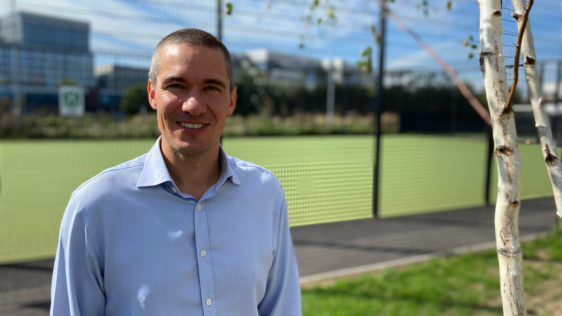 man in a blue shirt beside a sports field