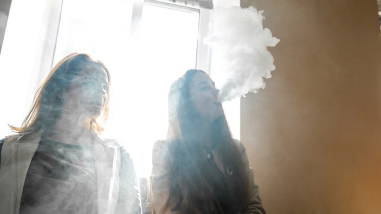 A teenager blowing vape smoke