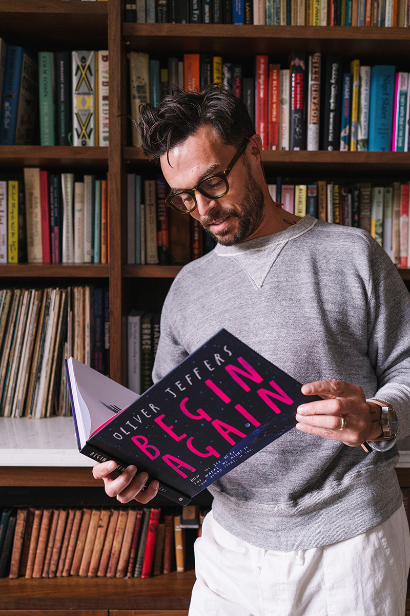 Oliver Jeffers reading his book beside a bookshelf