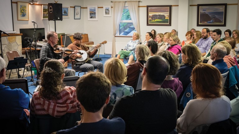 People sitting in a classroom listening to musicians