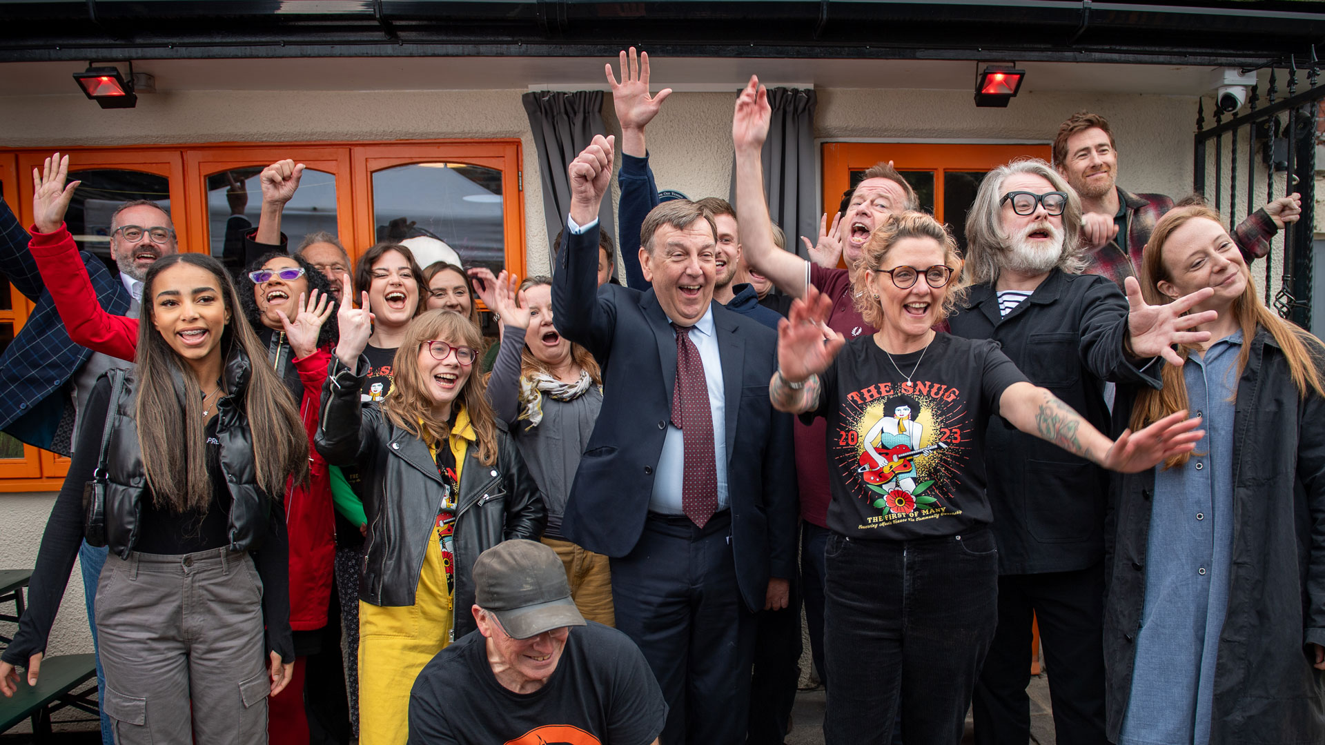 a crowd of people celebrating outside The Snug in Manchester