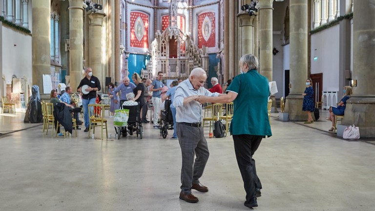 Two people dance in front of a small orchestra in a church