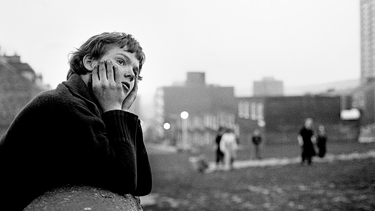 Black and white photo of child leaning elbows on a wall