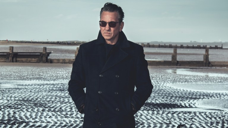 Richard Hawley walking on the beach in his coat