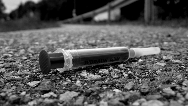 Black and white pic of discarded hypodermic needle