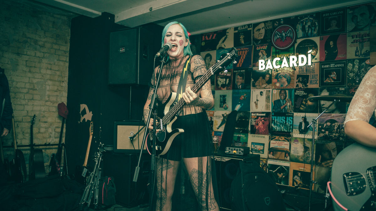 A girl with blue hair playing a guitar and signing