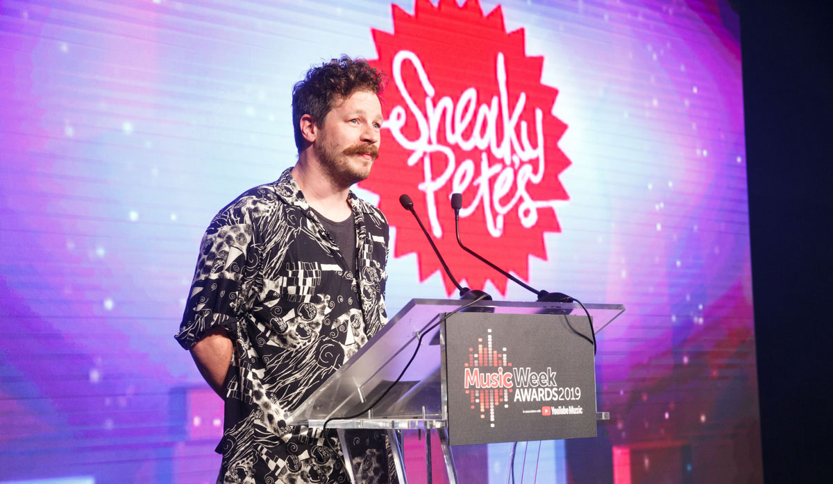 Nick Stewart at an awards in front of the Sneaky Pete's logo