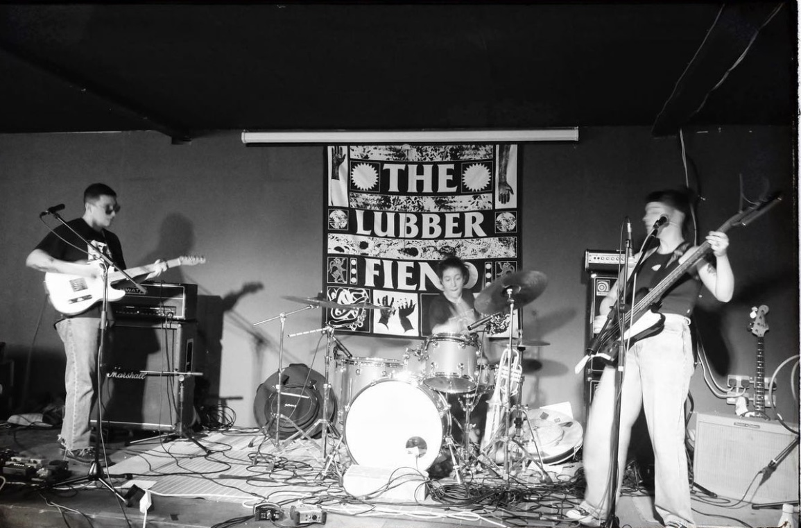 Sarah Rose Johnson performing in punk band Muckle in front of the Lubber Fiend banner