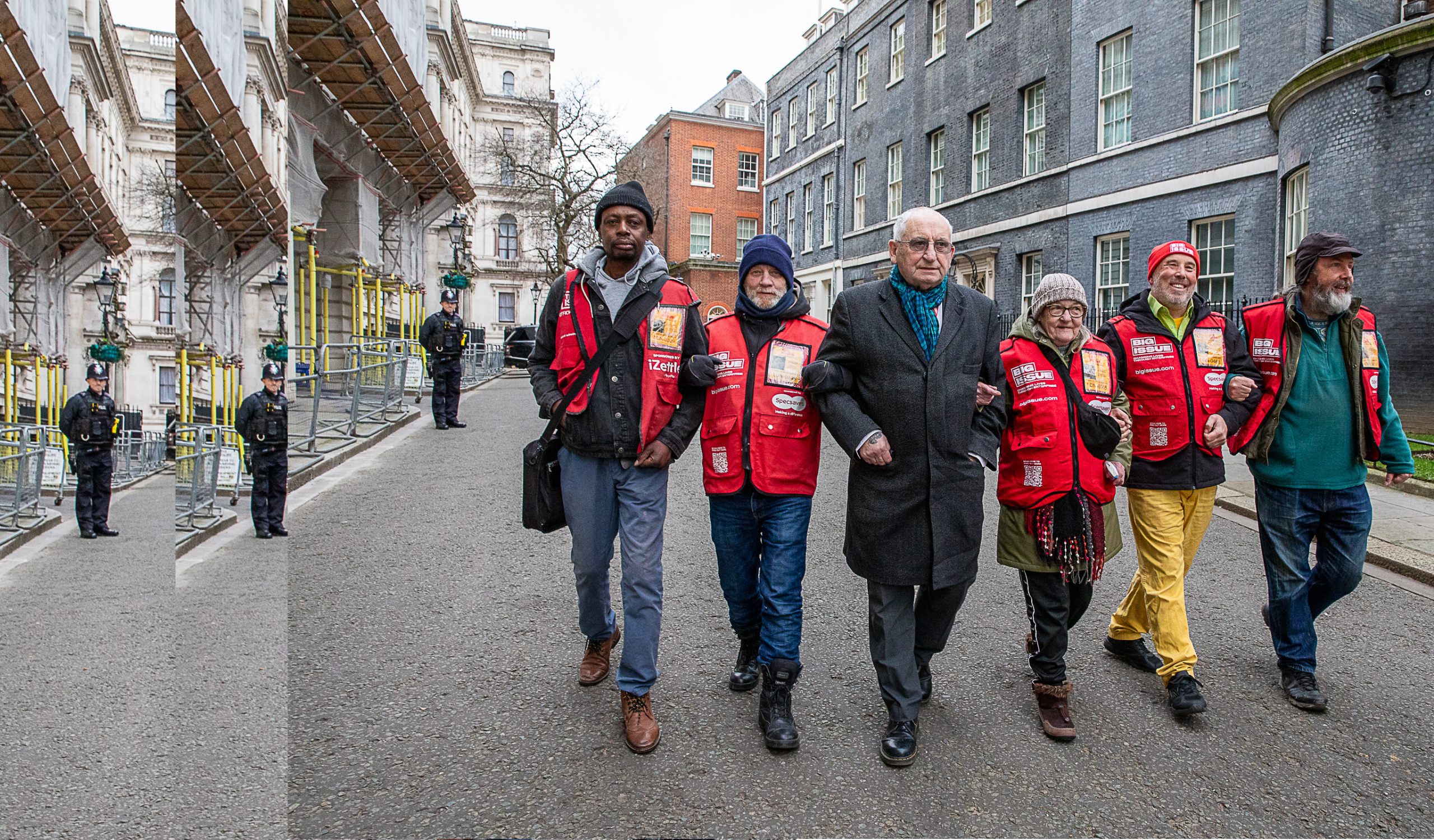 A group of Big Issue vendors and Lord Bird walk arm in arm on their way back from 10 Downing Street