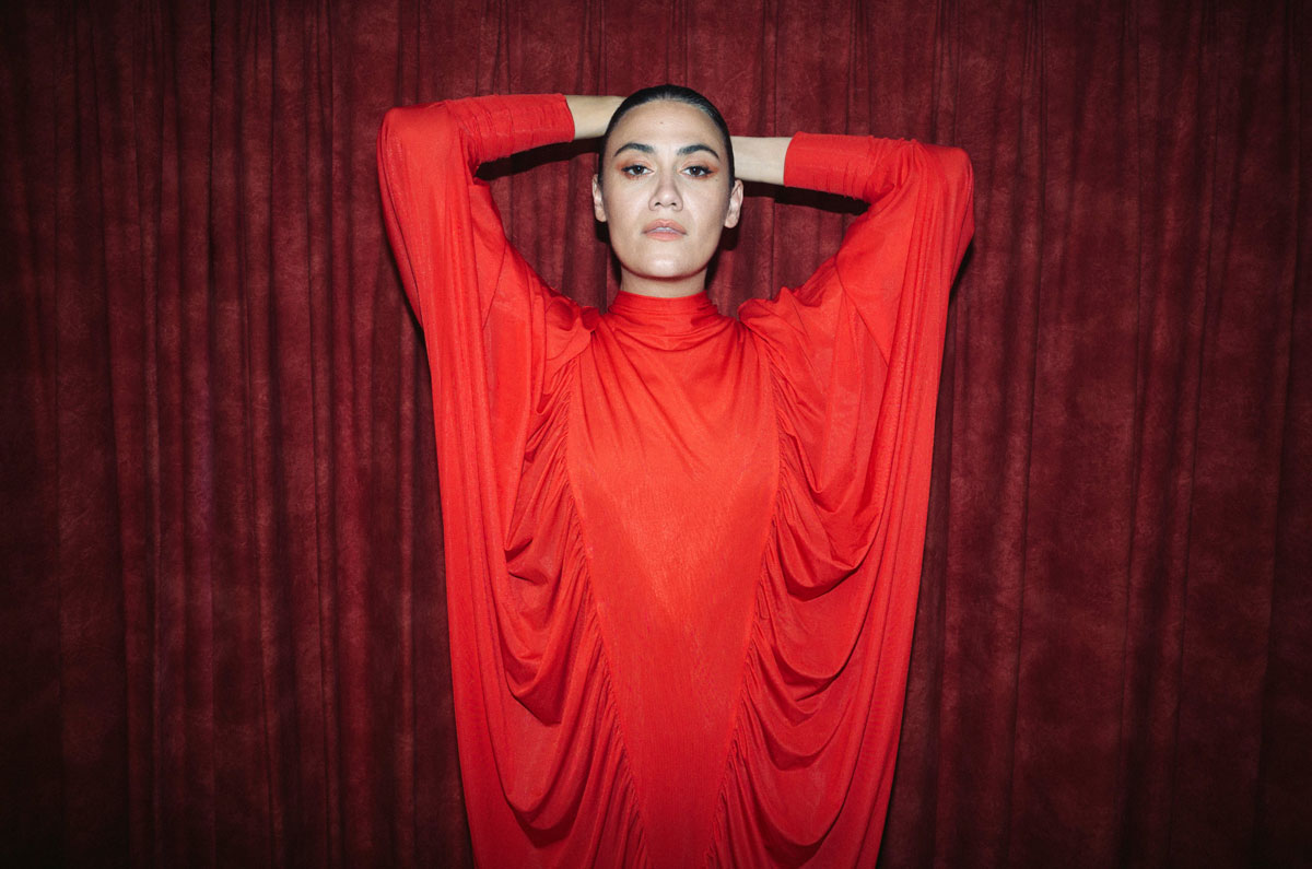 Nadine Shah in front of a red velvet curtain