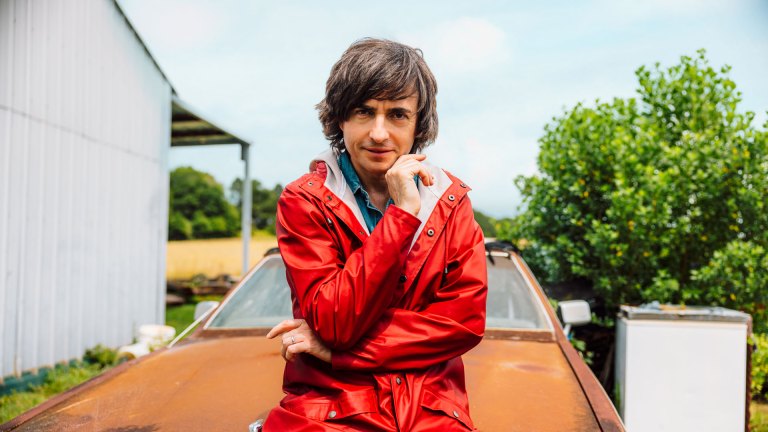 Danny Robins on set for Uncanny USA sitting on a rusty car