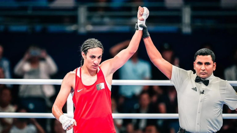 Algerian boxer Imane Khelif with her arm being raised in victory by a referee following a boxing match