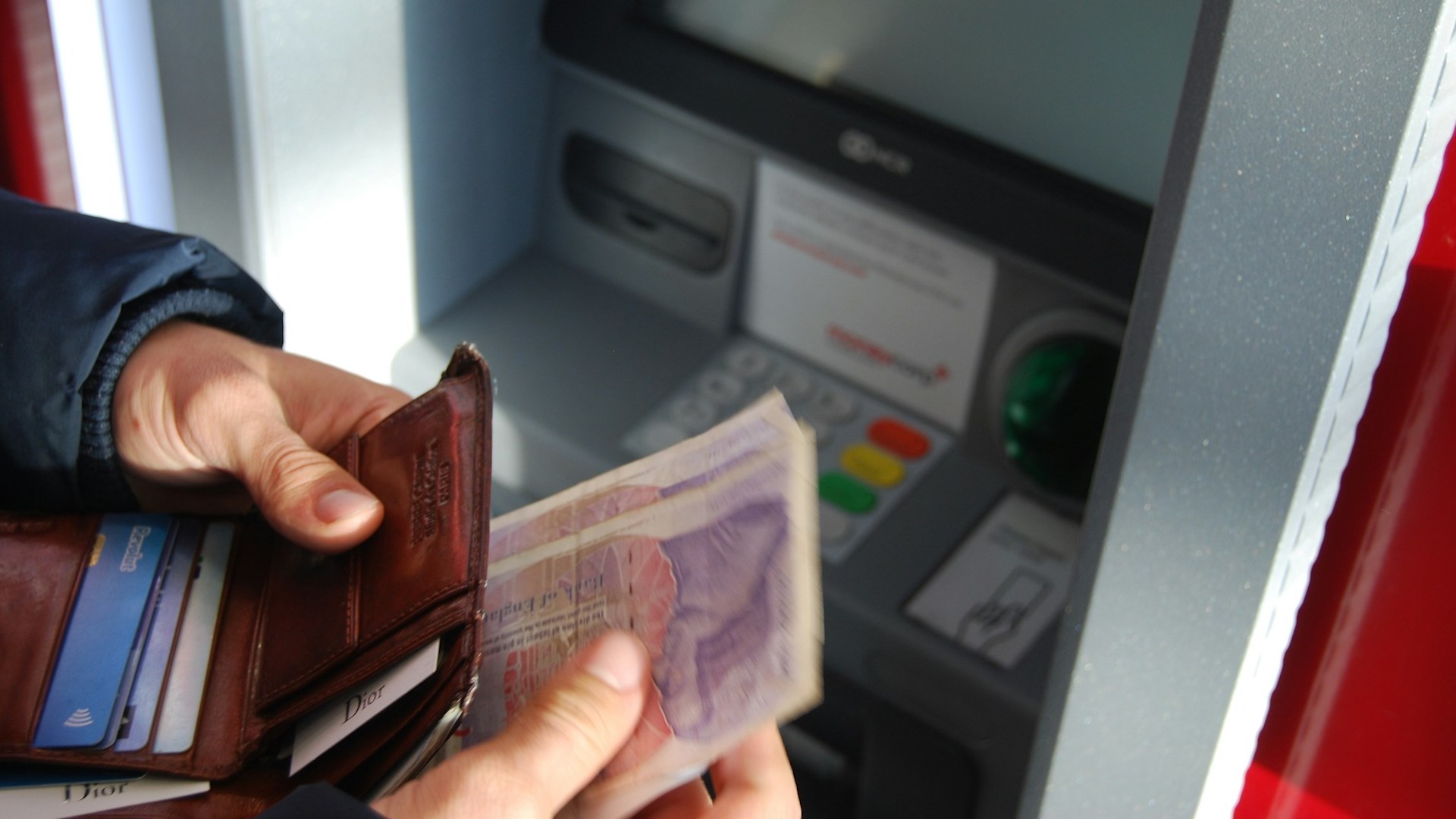 a person handling £20 notes in front of a cash machine / universal credit advance payment