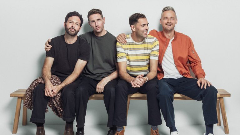 Pop/rock band Keane sat on a bench