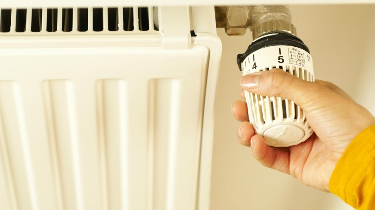a person turning a thermostat on a radiator