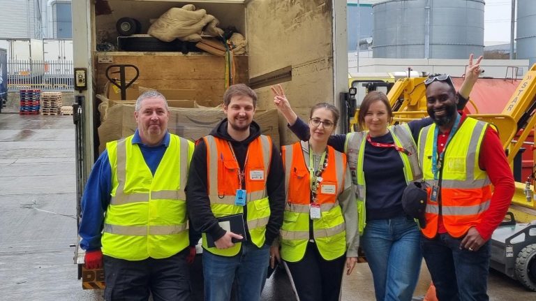 A group of people in reflective vests stand by a van