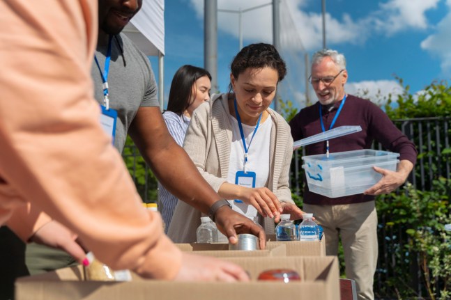 People packing boxes at a food bank. Representing the type of organisation that might seek social impact financing.