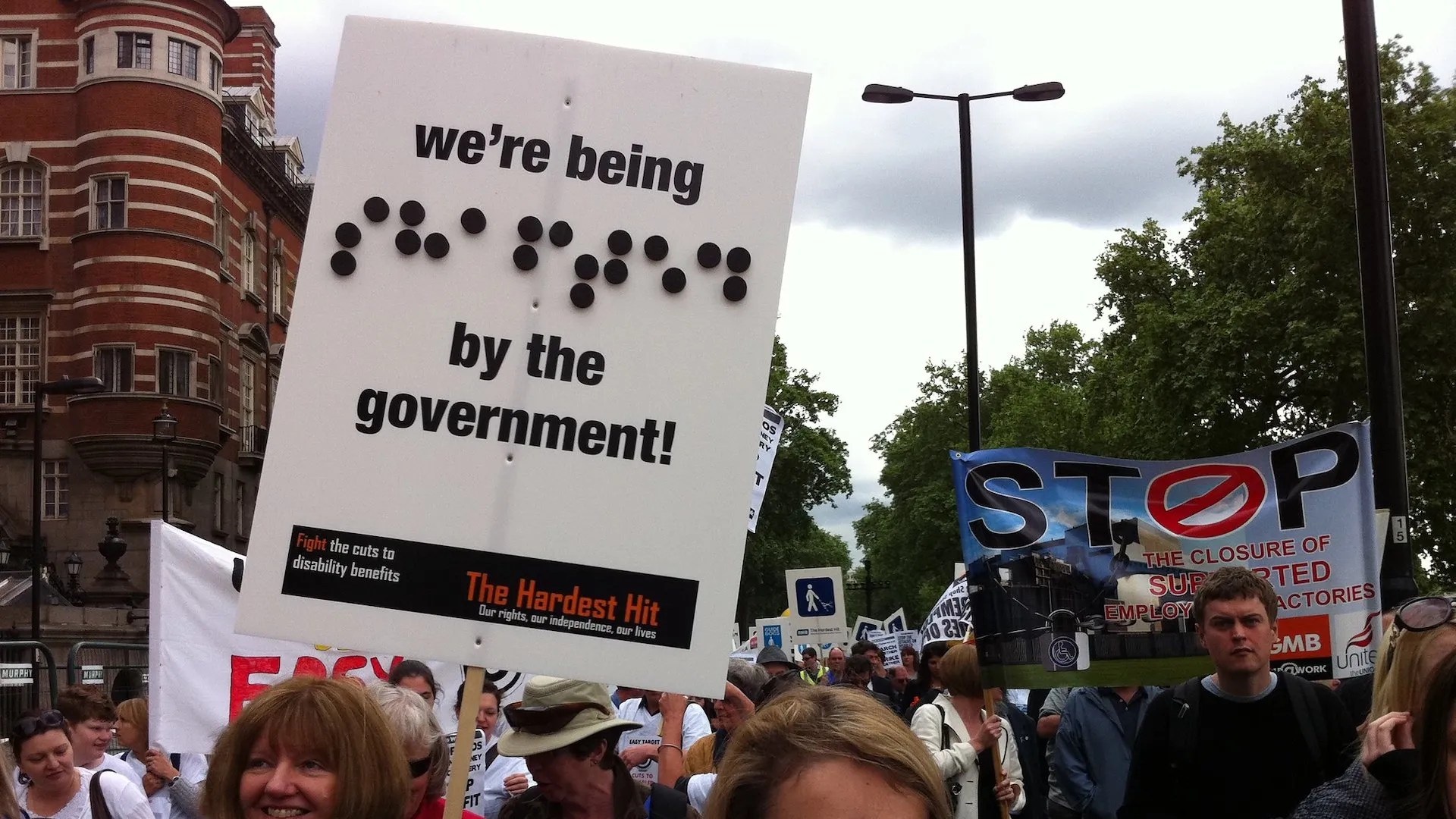 "We're being... by the government", a poster warns at a disability benefits protest.