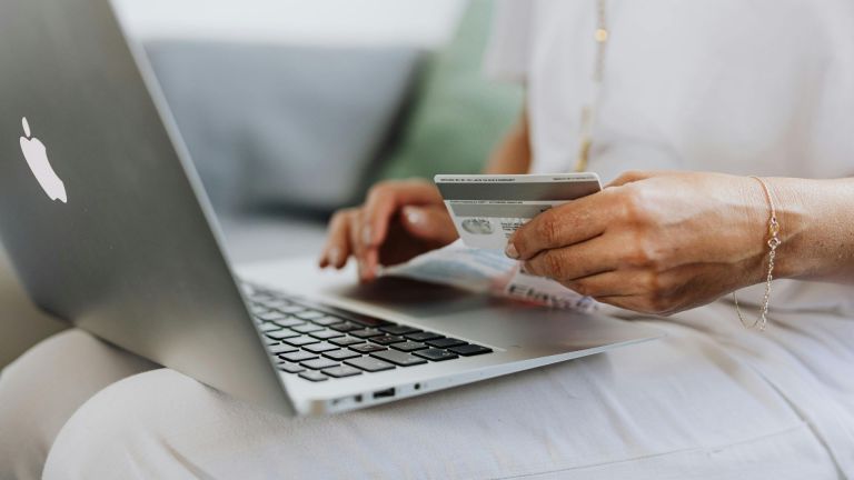 Stock image of a person online shopping with their credit card in their hand