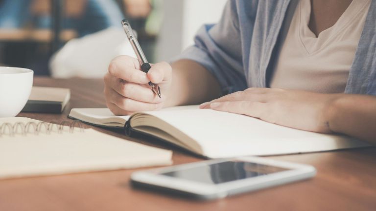 Stock image of a woman writing with a pen and paper