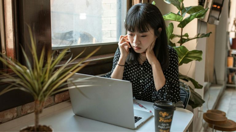 Stock image of a woman working on a laptop in a coffee shop