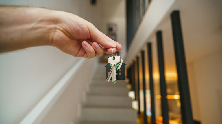 a landlord's hand holding keys on a stairway