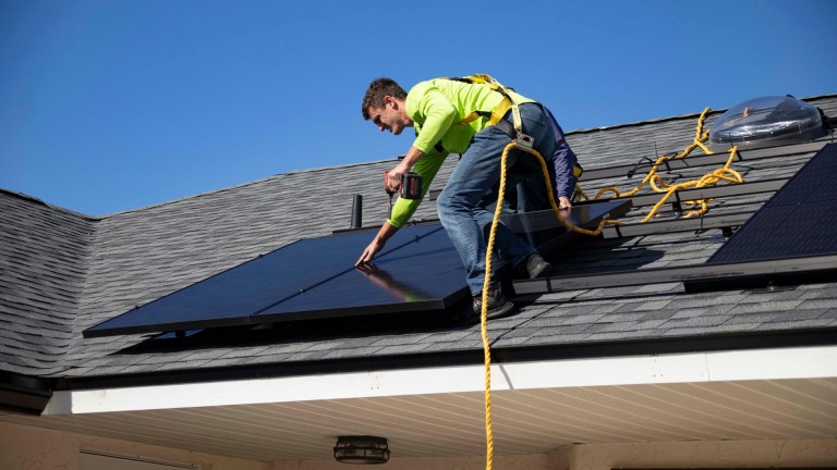 a man fitting solar panels to a house