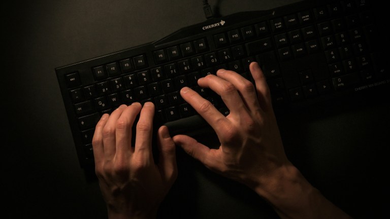 Hands typing on a keyboard/ Caption: Could AI predict murder?