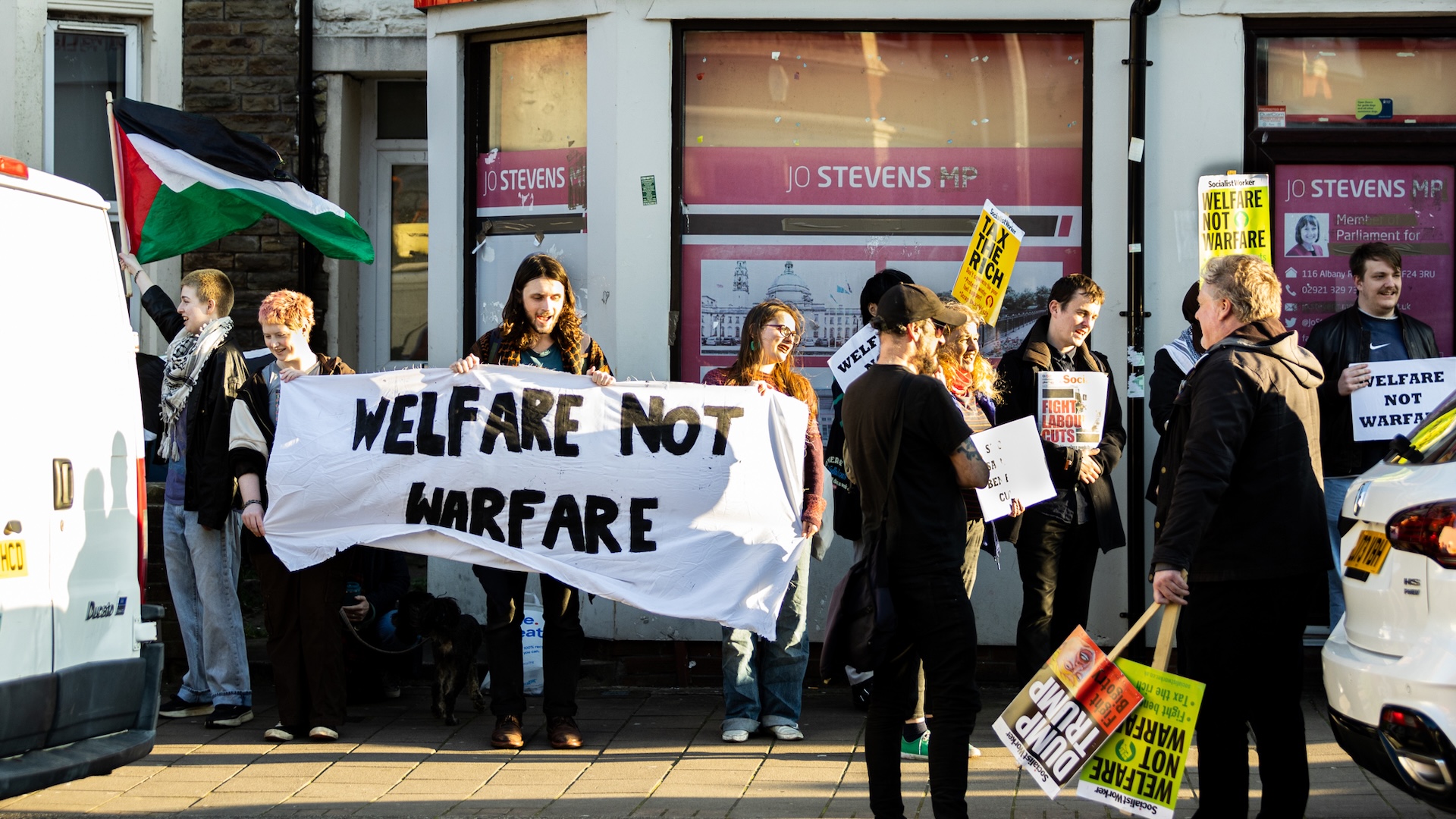 Protesters in Cardiff outside their local MP's office with a sign saying 'welfare not warfare'