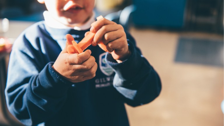 a boy in school uniform eating a carrot