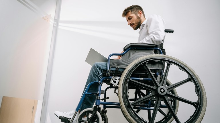 a man in a wheelchair working at a laptop