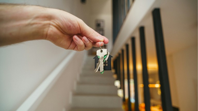 a renter holding a set of keys on the stairs of a home