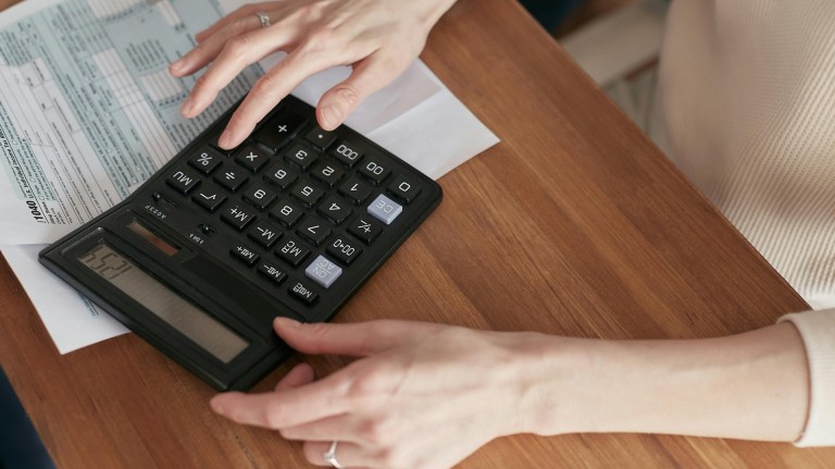 a person paying a bill and working out on a calculator