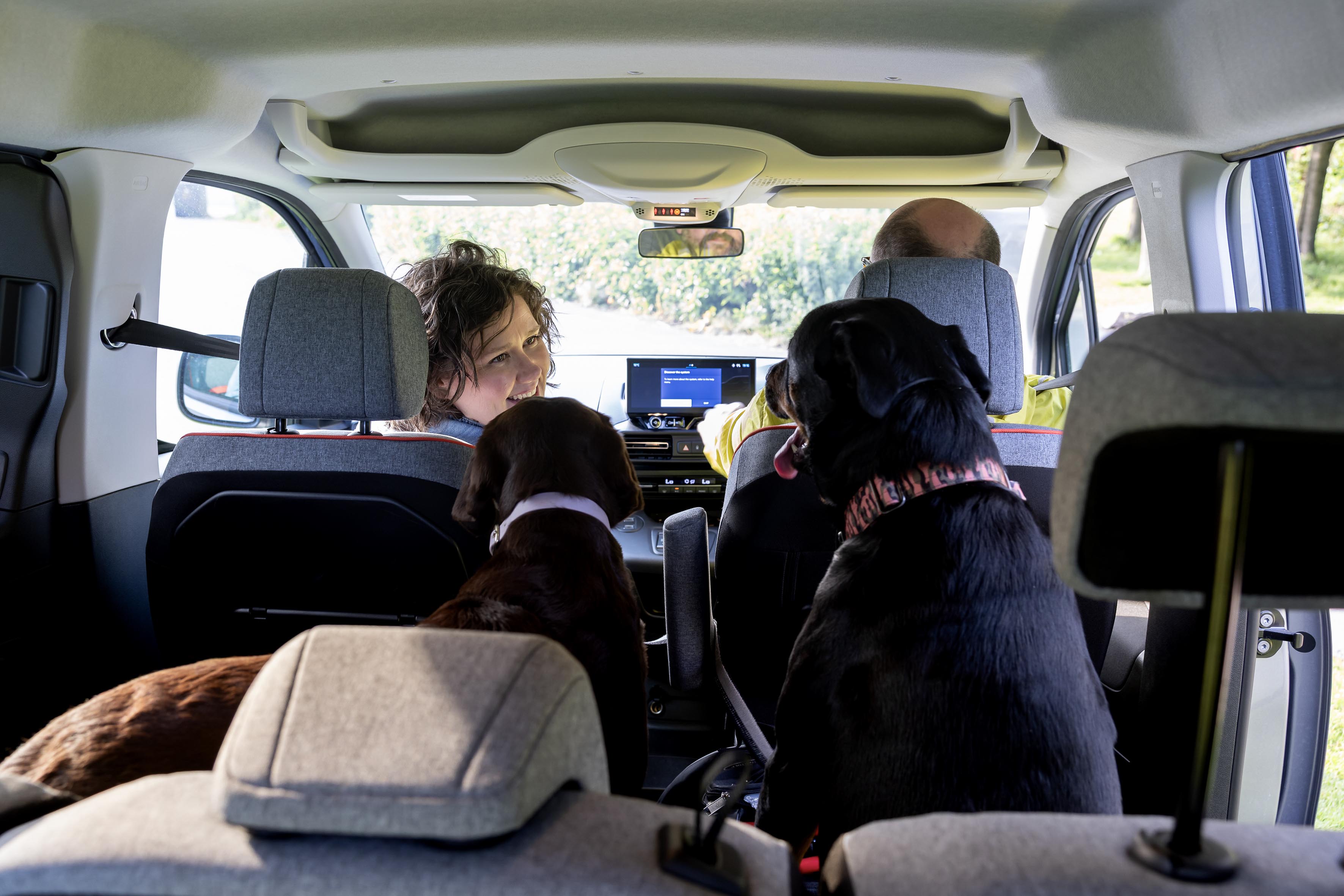 Interior view of Citroën ë-Berlingo electric car showing family with dogs in spacious cabin and touchscreen dashboard