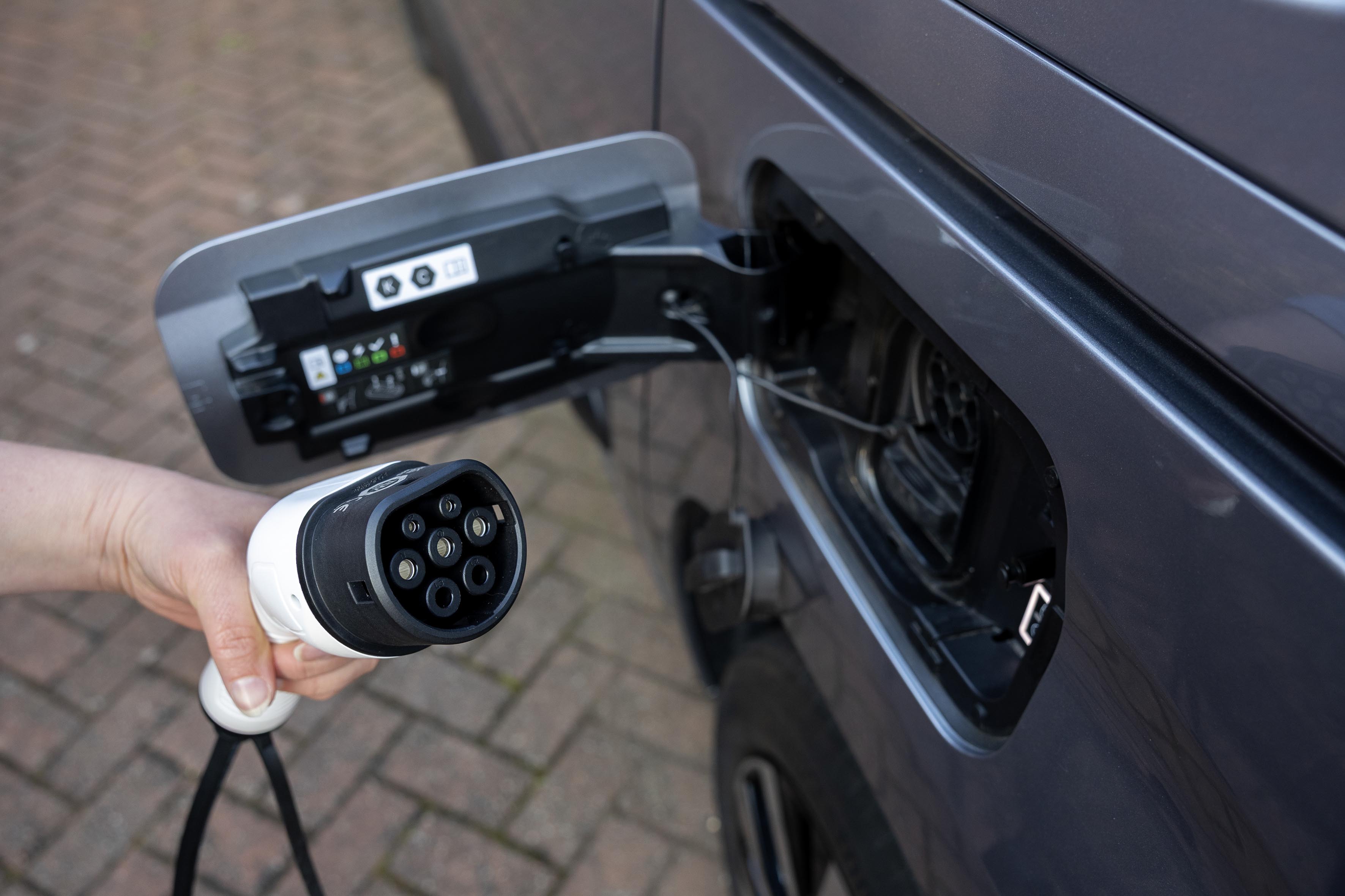 Hand holding CCS rapid charging cable plugged into Citroën ë-Berlingo electric car charging port