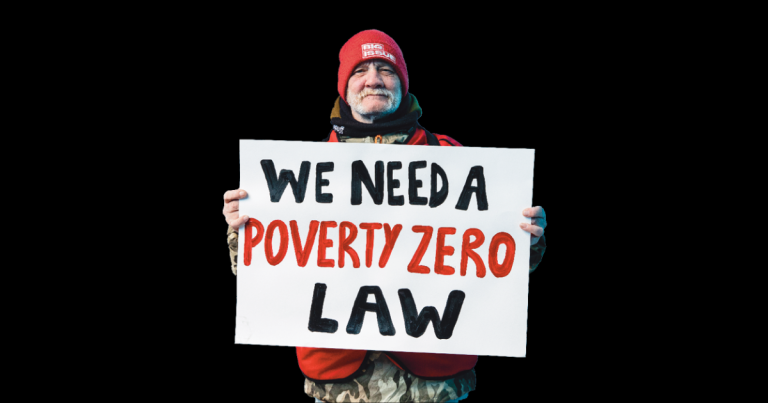 big issue vendor holding up a 'we need a poverty zero law' sign