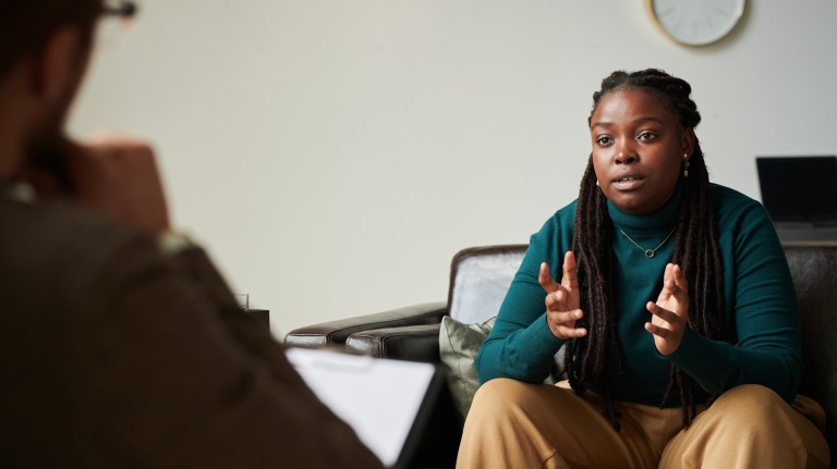 A black woman sitting on a sofa speaking to a psychologist
