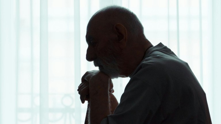 silhouette of an elderly man leaning on a walking stick