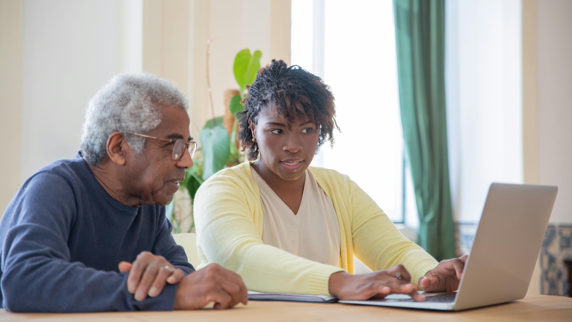 Image of pensioner and young woman looking at laptop