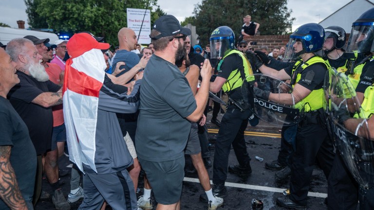 Far-right anti-immigration protestors scuffle with a cordon of riot police outside the Bell Hotel in Epping, Essex