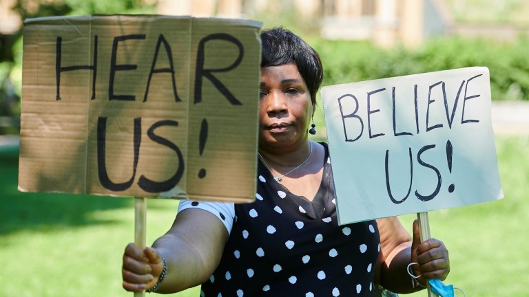 A woman holding a sign calling for people to 'Hear us' and 'Believe us'. Image: Simon Tang/ Women for Refugee Women