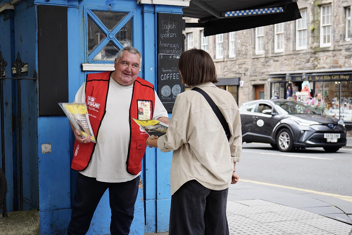 George wearing the Specsavers-sponsored tabard while selling magazines, connecting the clinic to the broader Big Issue partnership