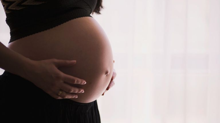 Stock image of a pregnant person's baby bump