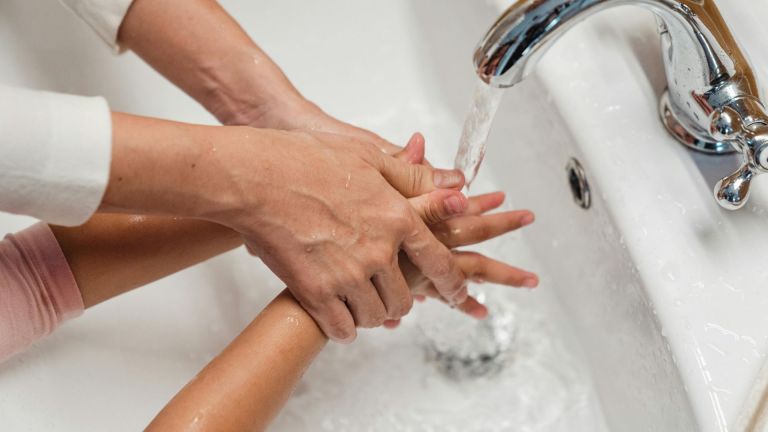 Image of parent washing child's hands in a sink